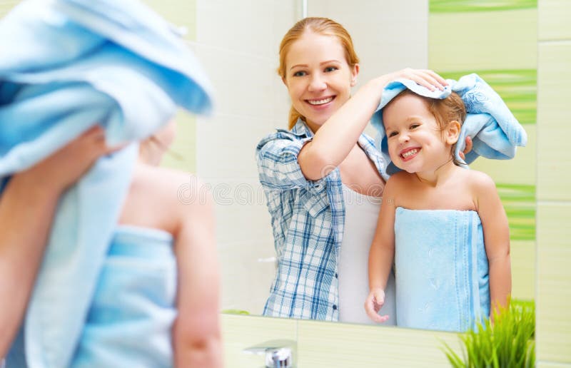 Familia feliz en cuarto de baño madre de un niño con el cabello seco de la toalla