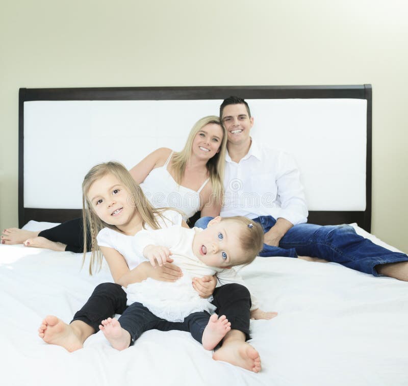 Familia feliz en la cama blanca en el dormitorio fotos de archivo libres de regalías Familia feliz en la cama blanca en el dormitorio fotos de archivo libres de regalías