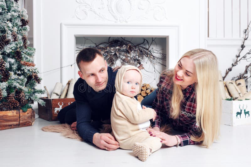 Familia feliz en la Navidad Los padres y el bebé que mienten en el piso y la sonrisa imagenes de archivo Familia feliz en la Navidad Los padres y el bebé que mienten en el piso y la sonrisa imagenes de archivo
