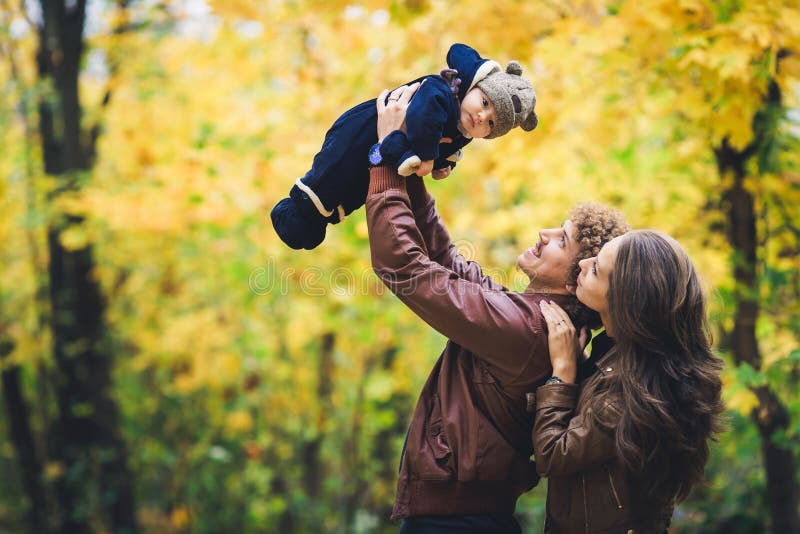 Familia feliz joven en otoño en parque El padre alegre lanza a su hijo para arriba foto de archivo Familia feliz joven en otoño en parque El padre alegre lanza a su hijo para arriba foto de archivo