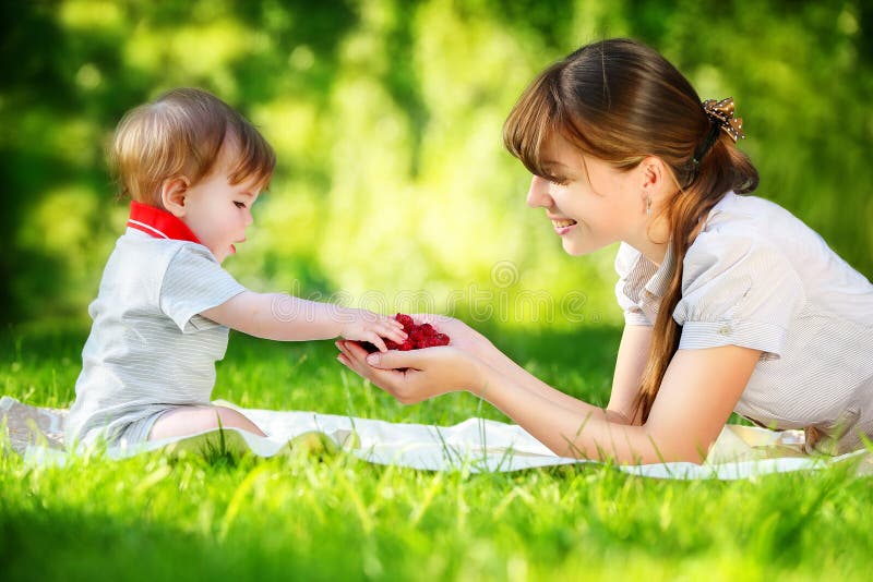 Familia feliz, mamá y pequeño hijo divirtiéndose en el parque Raspber imagenes de archivo Familia feliz, mamá y pequeño hijo divirtiéndose en el parque Raspber imagenes de archivo