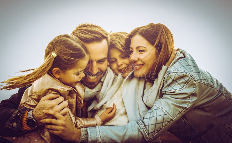 Familia feliz que abraza y que sonríe al aire libre