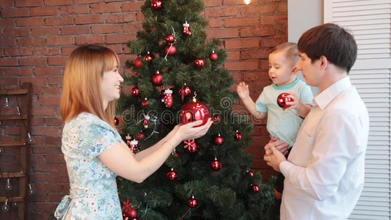 Familia feliz que adorna el árbol de navidad