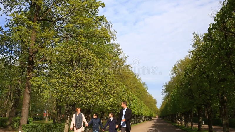 Familia feliz que camina junto caminando en un parque en capas y chaquetas en un día soleado metrajes Familia feliz que camina junto caminando en un parque en capas y chaquetas en un día soleado metrajes