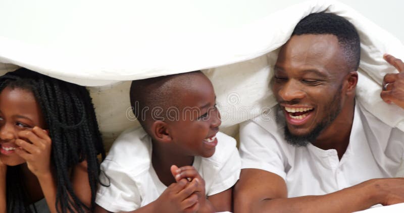 Familia feliz que miente en cama y que se divierte