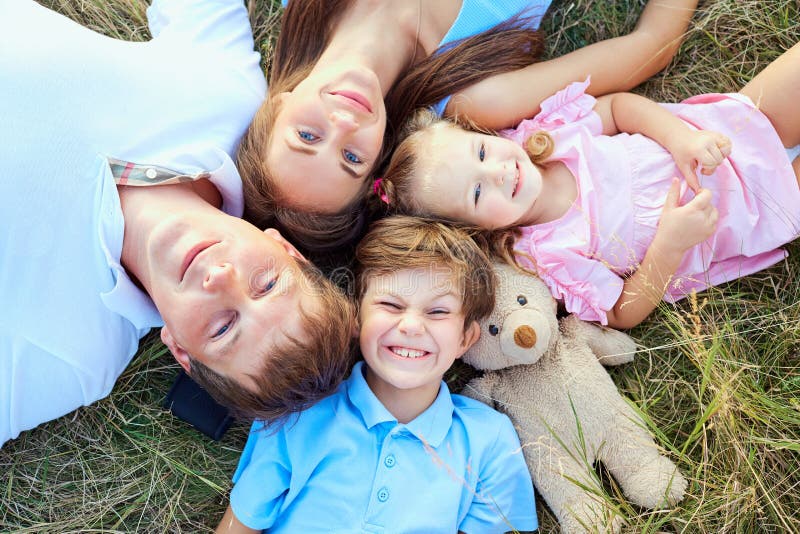 Familia feliz que miente en la opinión del primer de la hierba desde arriba fotos de archivo Familia feliz que miente en la opinión del primer de la hierba desde arriba fotos de archivo
