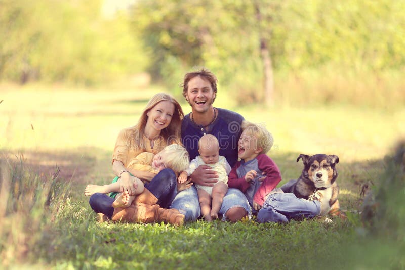 Familia feliz que ríe así como perro afuera