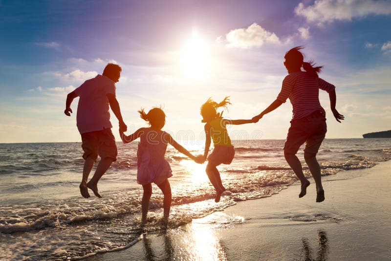 Familia feliz que salta en la playa
