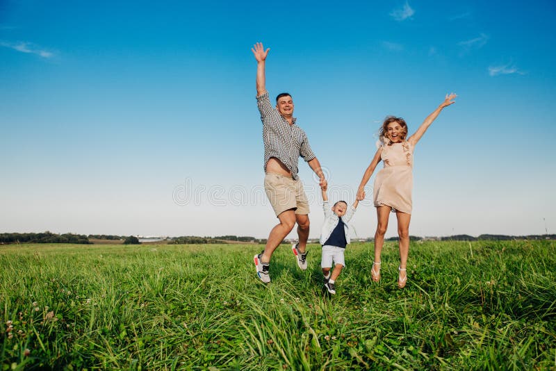 Familia feliz que salta junto en el campo en día soleado foto de archivo libre de regalías Familia feliz que salta junto en el campo en día soleado foto de archivo libre de regalías