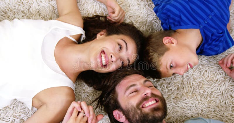 Familia feliz que sonríe y que miente en una alfombra