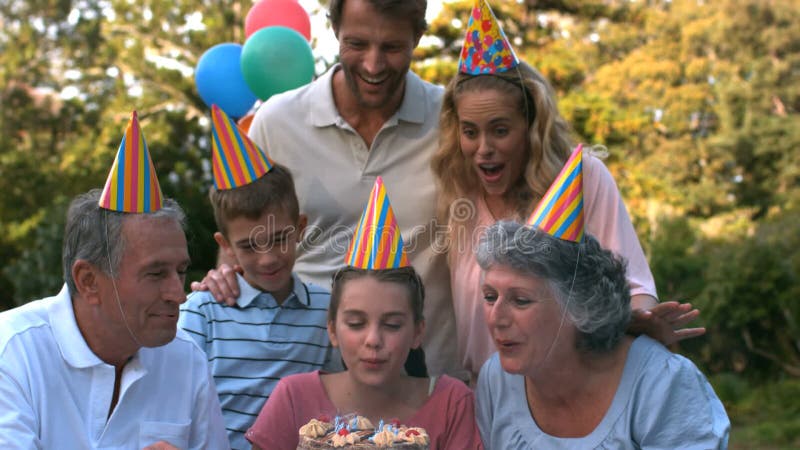 Familia feliz que sopla las velas de la torta de cumpleaños