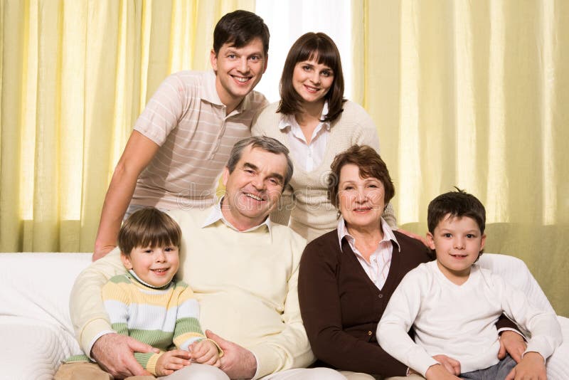 Portrait of senior and young couples with their children looking at camera at home. Portrait of senior and young couples with their children looking at camera at home