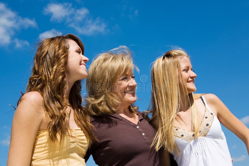 Beautiful grandmother & granddaughters laughing in profile against a blue sky. Beautiful grandmother & granddaughters laughing in profile against a blue sky.