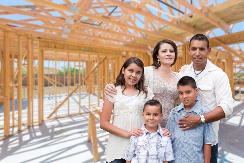 Young Hispanic Family On Site Inside New Home Construction Framing. Young Hispanic Family On Site Inside New Home Construction Framing.