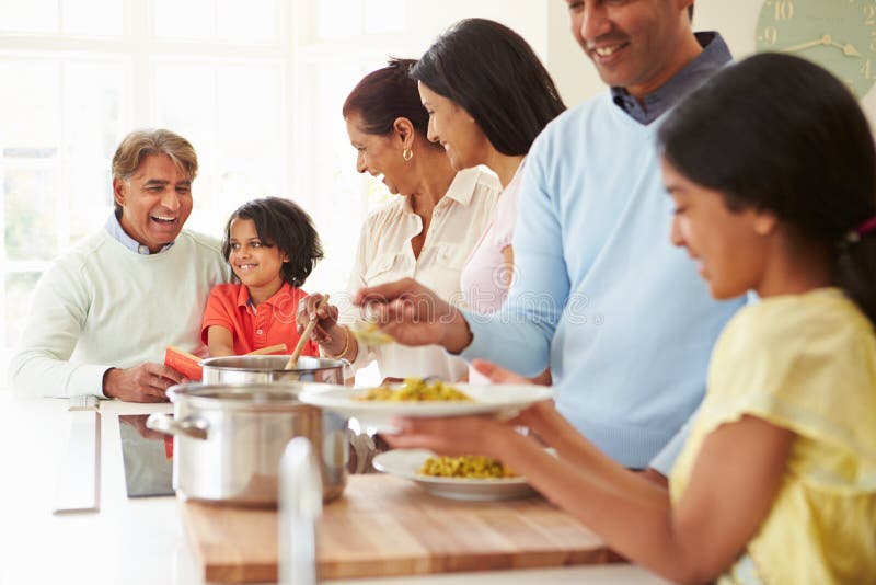 Familia india de la generación multi que cocina la comida en casa