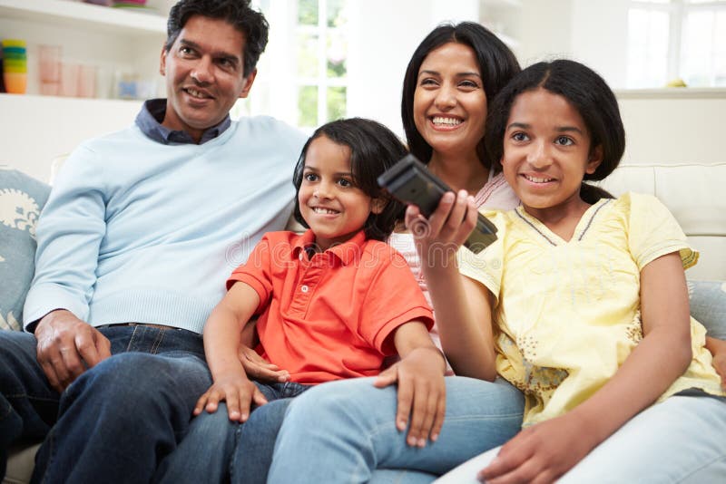 Familia india que se sienta en Sofa Watching TV junto imagen de archivo Familia india que se sienta en Sofa Watching TV junto imagen de archivo