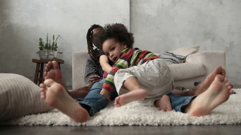 Familia interracial feliz que se sienta descalzo en piso