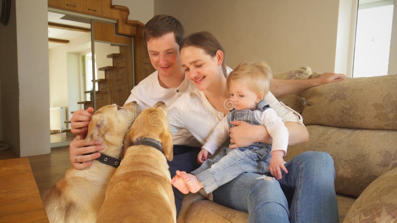 Familia joven alegre con dos animales domésticos de los perros en casa Emociones positivas