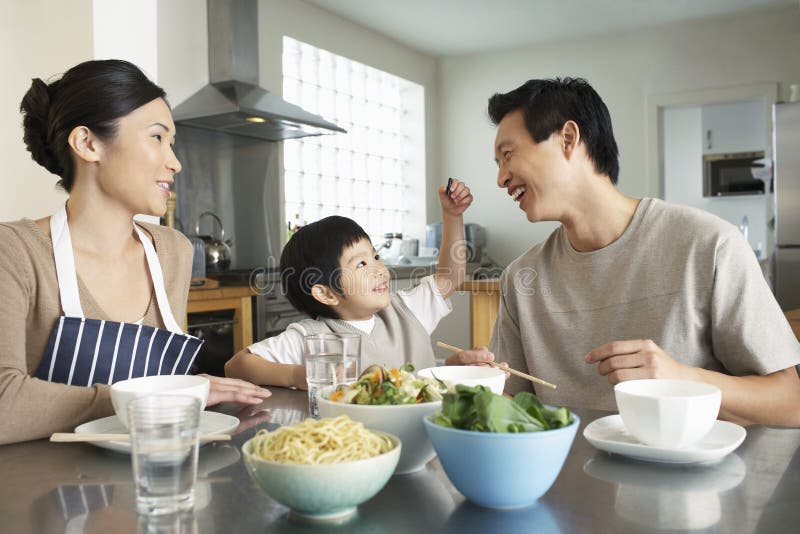 Familia joven feliz que disfruta de la comida fotografía de archivo libre de regalías Familia joven feliz que disfruta de la comida fotografía de archivo libre de regalías