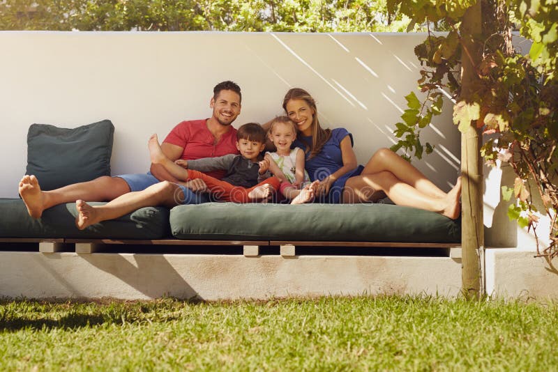 Familia joven feliz que se sienta en patio imagenes de archivo Familia joven feliz que se sienta en patio imagenes de archivo