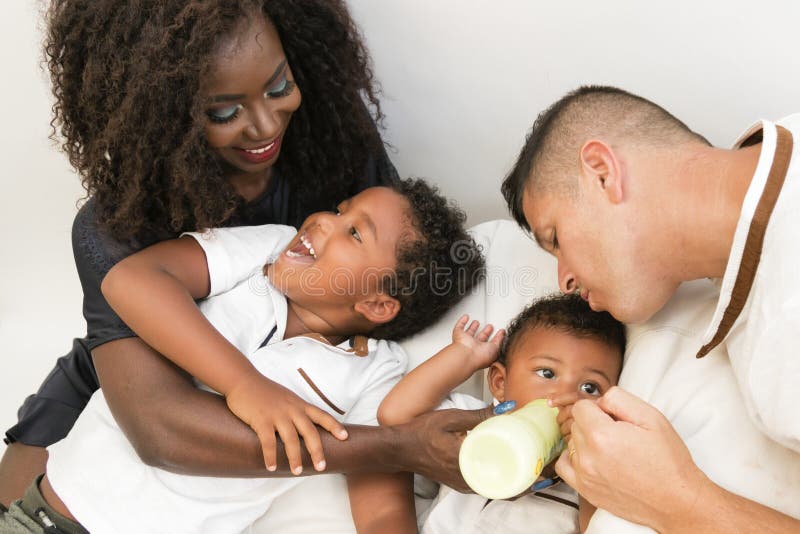 Familia joven Padres que alimentan a un niño infantil con leche Multi y foto de archivo libre de regalías Familia joven Padres que alimentan a un niño infantil con leche Multi y foto de archivo libre de regalías