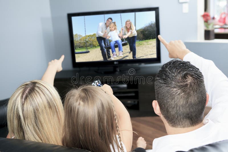 Familia joven que ve la TV junto en casa fotografía de archivo libre de regalías Familia joven que ve la TV junto en casa fotografía de archivo libre de regalías