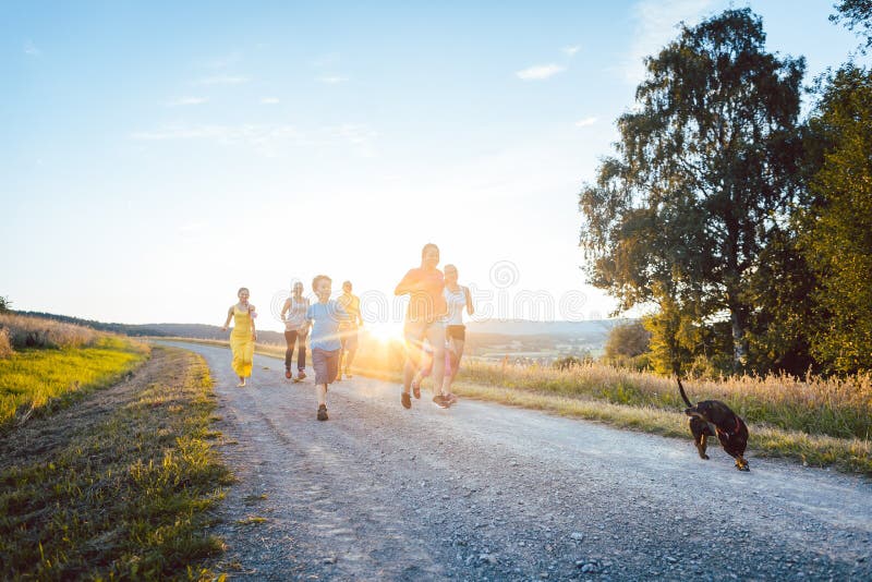 Familia juguetona que corre y que juega en una trayectoria en paisaje del verano foto de archivo Familia juguetona que corre y que juega en una trayectoria en paisaje del verano foto de archivo