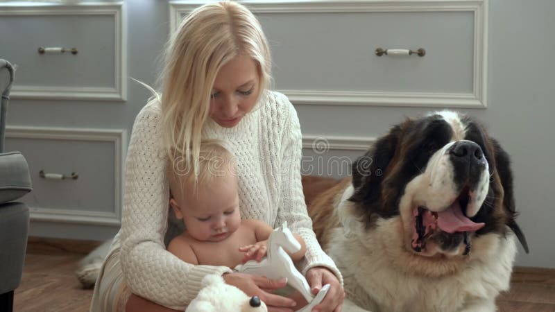 Familia linda que se relaja junto en el sofá con su perro en la manta en sala de estar en casa Madre con el juego del hijo en