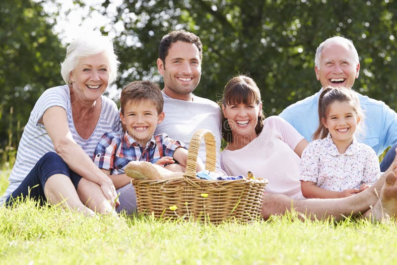 Familia multi de la generación que disfruta de comida campestre en campo imágenes de archivo libres de regalías Familia multi de la generación que disfruta de comida campestre en campo imágenes de archivo libres de regalías