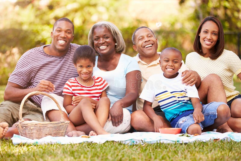 Multi Generation Family Enjoying Picnic In Garden Together. Multi Generation Family Enjoying Picnic In Garden Together