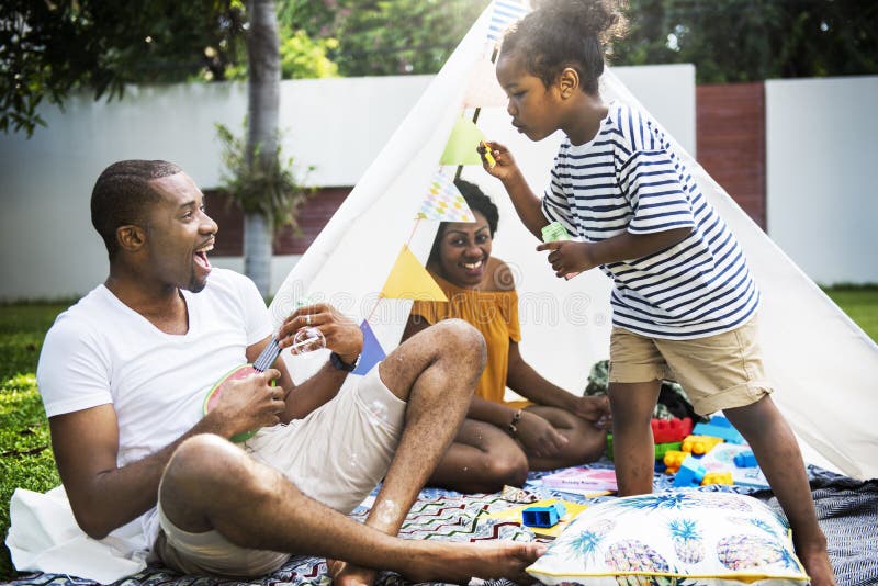 Familia negra que disfruta del verano junto en el jabón que sopla b del patio trasero