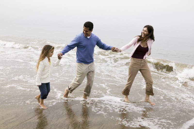 Familia que camina a través de la resaca en la playa foto de archivo libre de regalías Familia que camina a través de la resaca en la playa foto de archivo libre de regalías