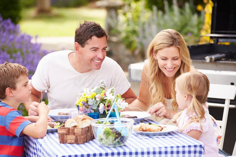 Familia que disfruta de la comida al aire libre en jardín