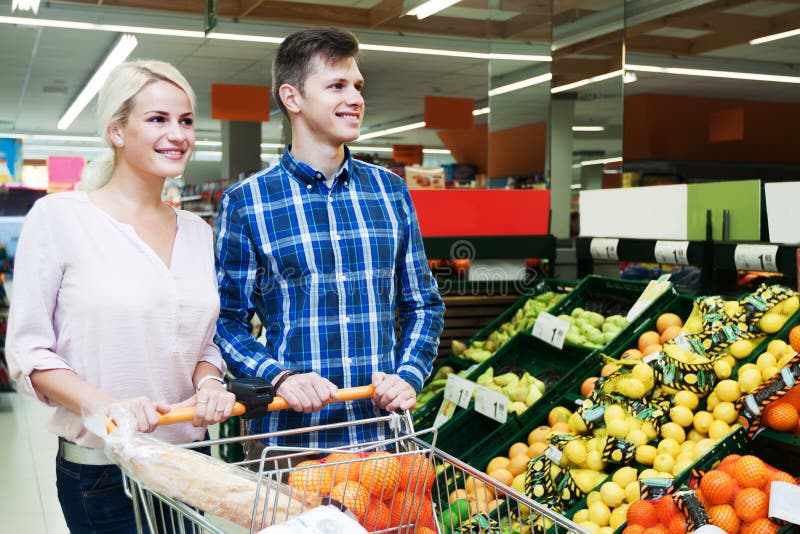 Familia que elige las frutas estacionales en la sección del ultramarinos fotografía de archivo libre de regalías Familia que elige las frutas estacionales en la sección del ultramarinos fotografía de archivo libre de regalías