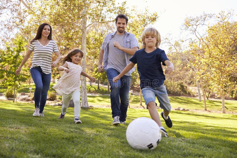 Familia que juega al fútbol en parque junto foto de archivo Familia que juega al fútbol en parque junto foto de archivo