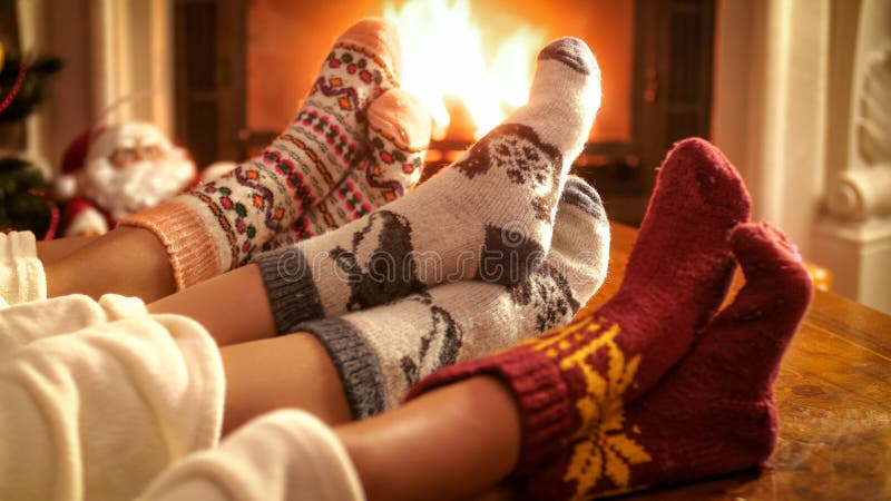 Familia que lleva los calcetines de lana hechos punto que calientan pies en la chimenea el Nochebuena imagen de archivo Familia que lleva los calcetines de lana hechos punto que calientan pies en la chimenea el Nochebuena imagen de archivo