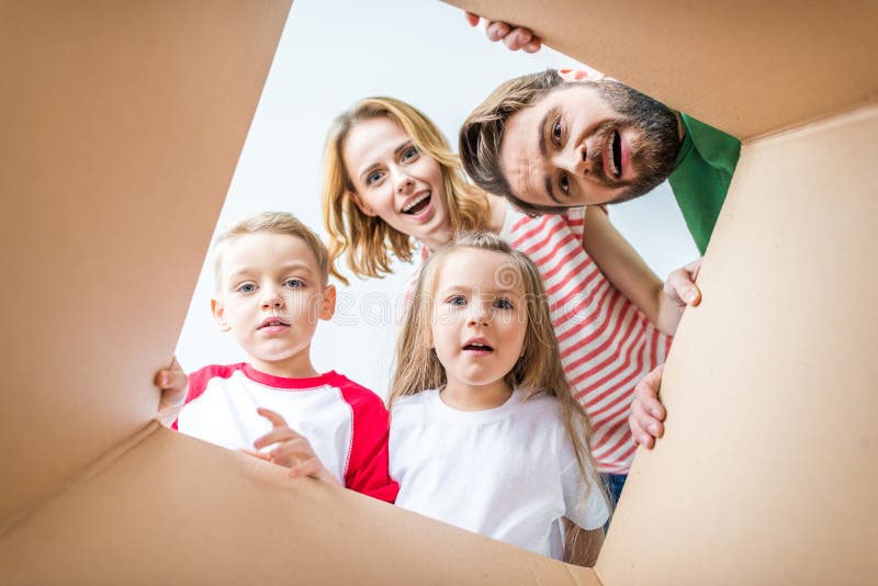 Familia que mira a escondidas de la caja de cartón fotografía de archivo Familia que mira a escondidas de la caja de cartón fotografía de archivo
