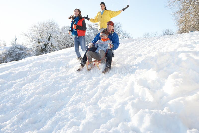 Familia que tiene colina de Sledging abajo Nevado de la diversión fotografía de archivo libre de regalías Familia que tiene colina de Sledging abajo Nevado de la diversión fotografía de archivo libre de regalías