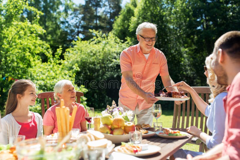 Familia que tiene la cena o barbacoa en el jardín del verano fotografía de archivo libre de regalías Familia que tiene la cena o barbacoa en el jardín del verano fotografía de archivo libre de regalías