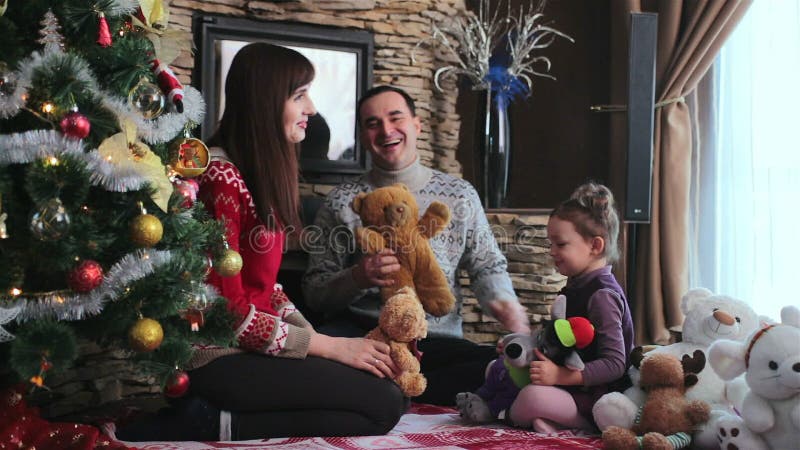 Familia se joacă cu fiica lor lângă pomul de Crăciun stock video
