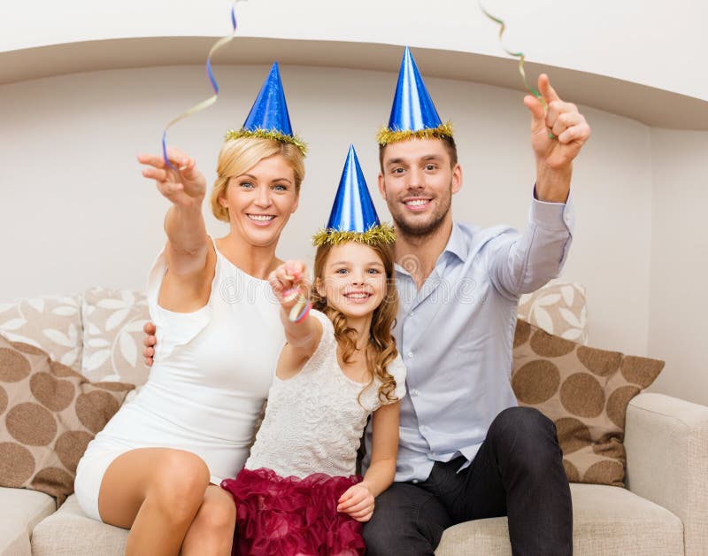 Familia sonriente en sombreros azules con la torta foto de archivo libre de regalías Familia sonriente en sombreros azules con la torta foto de archivo libre de regalías
