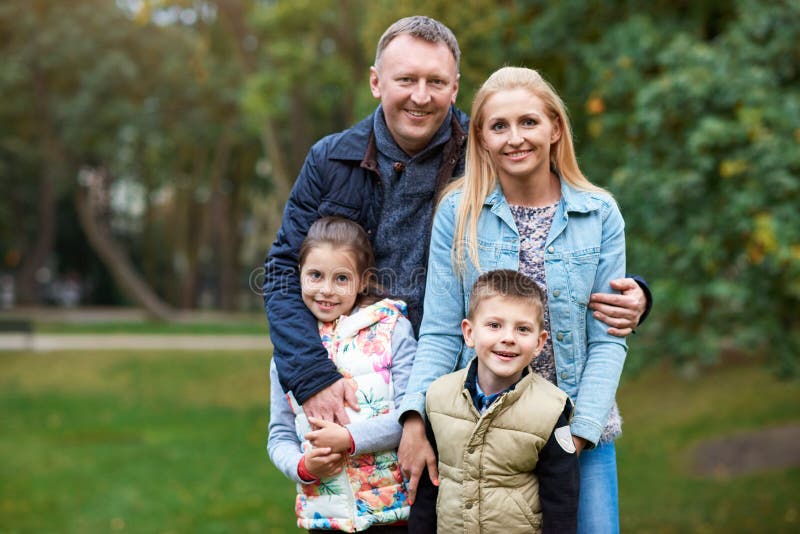 Familia sonriente que disfruta de un día del otoño en el parque imagen de archivo libre de regalías Familia sonriente que disfruta de un día del otoño en el parque imagen de archivo libre de regalías
