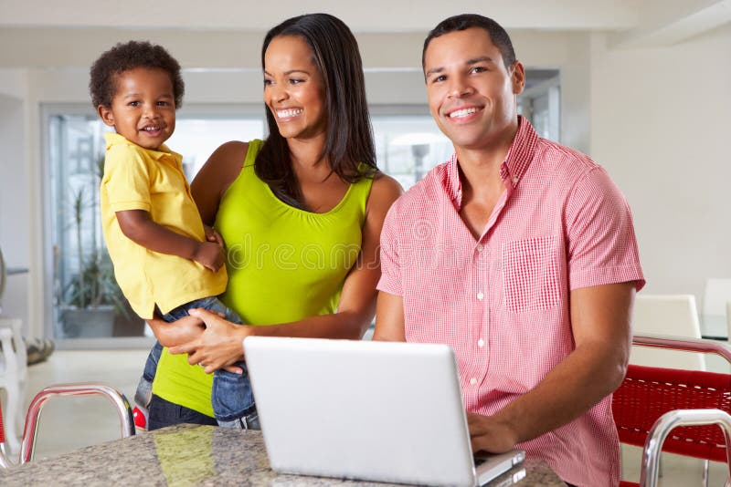 Familia usando el ordenador portátil en cocina junto imagenes de archivo Familia usando el ordenador portátil en cocina junto imagenes de archivo