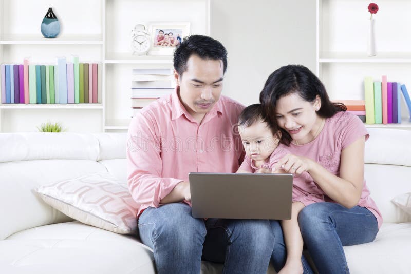 Familia usando un ordenador portátil en la sala de estar imagen de archivo Familia usando un ordenador portátil en la sala de estar imagen de archivo
