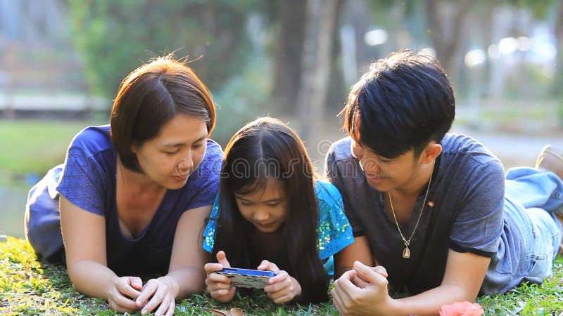 Familie asiatică fericită jucând jocuri în telefonul inteligent împreună stock video