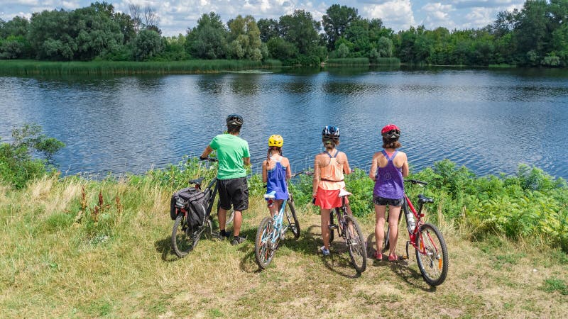 Family on bikes cycling outdoors, active parents and kids on bicycles, aerial view of happy family with children relaxing near beautiful river from above, sport and fitness concept. Family on bikes cycling outdoors, active parents and kids on bicycles, aerial view of happy family with children relaxing near beautiful river from above, sport and fitness concept