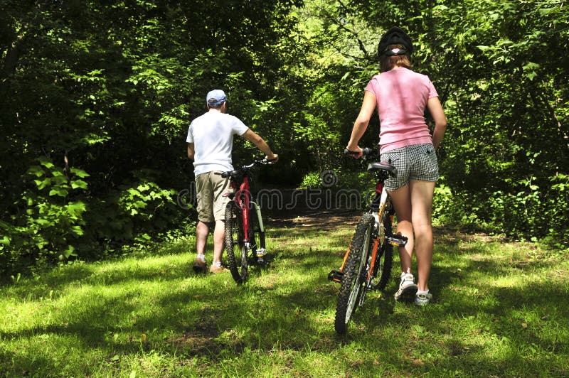 Teenage girl and her father with bicycles in summer park. Teenage girl and her father with bicycles in summer park