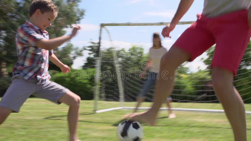 Familie care joacă fotbal în grădină împreună stock footage