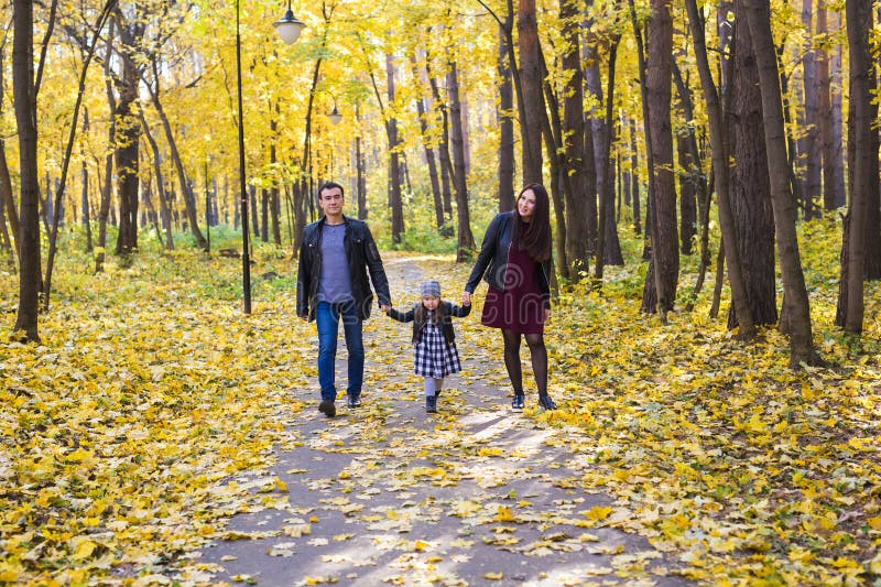 Familie, daling, mensenconcept - gemengde ras jonge familie die in park in de herfstdag lopen royalty-vrije stock foto Familie, daling, mensenconcept - gemengde ras jonge familie die in park in de herfstdag lopen royalty-vrije stock foto