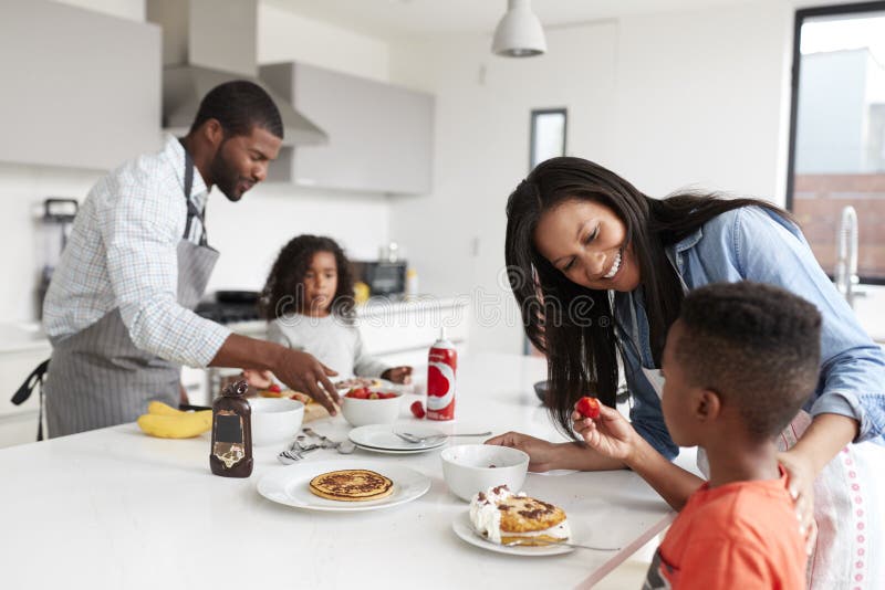 Familie in der K?che zu Hause, die zusammen Pfannkuchen macht lizenzfreies stockbild Familie in der K?che zu Hause, die zusammen Pfannkuchen macht lizenzfreies stockbild
